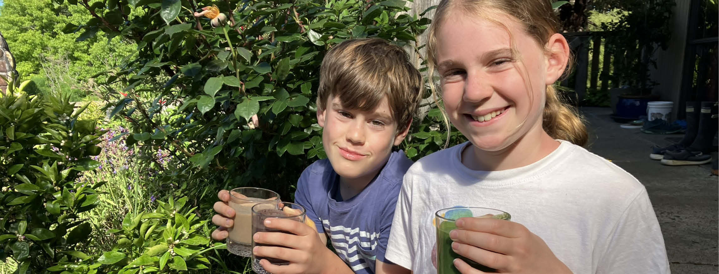 two kids enjoying healthy smoothies in the sunny outdoors