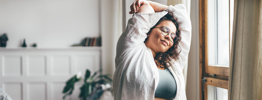 Woman wearing glasses stretching at home